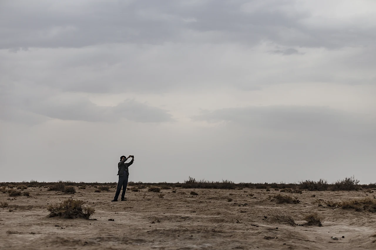 Person fotografiert eine weite Landschaft unter wolkenverhangenem Himmel