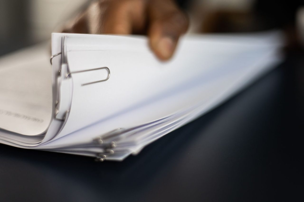 Hand sorts documents with paper clips, close-up