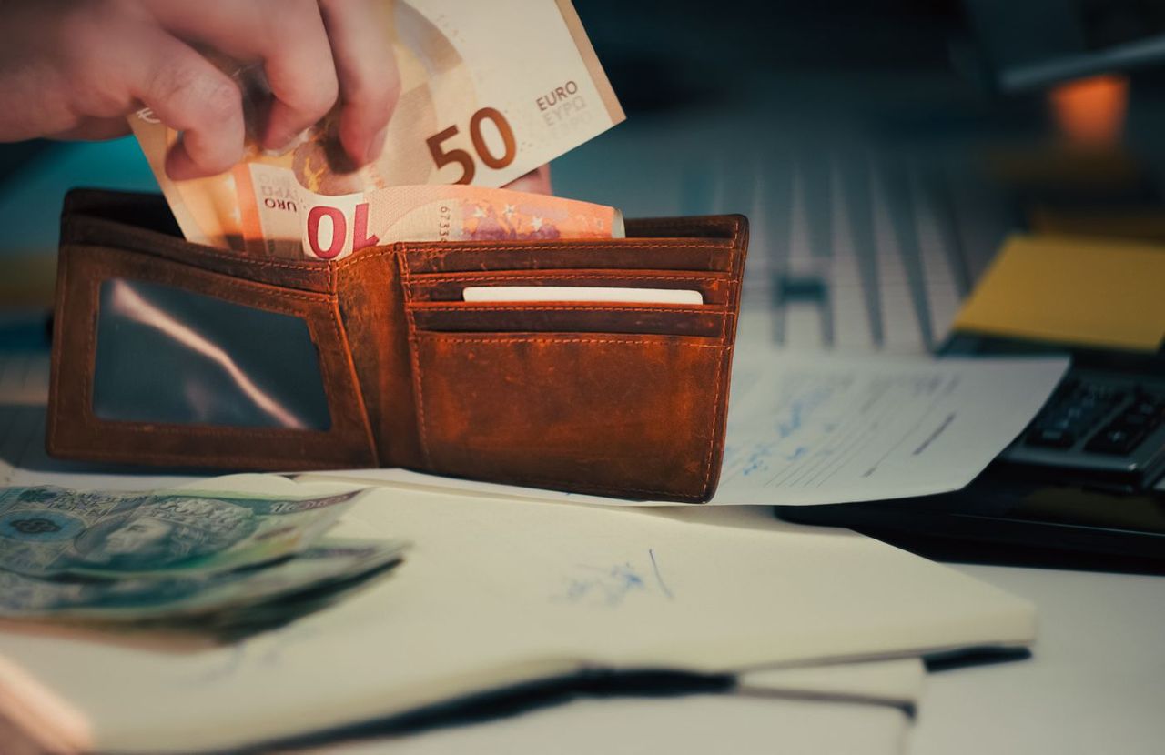 Geldbörse mit Euro-Banknoten und Unterlagen auf einem Schreibtisch