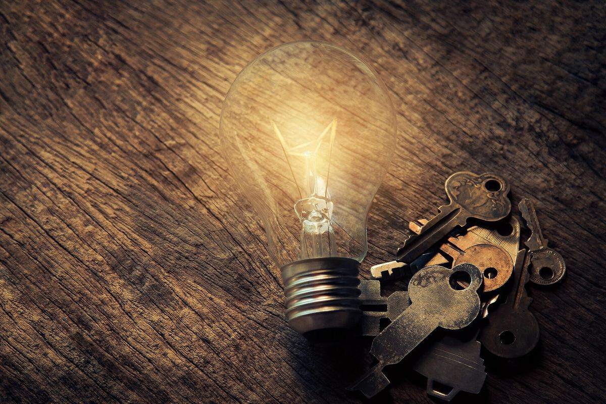 Keys and a light bulb on a wooden table, a symbol for access and solutions