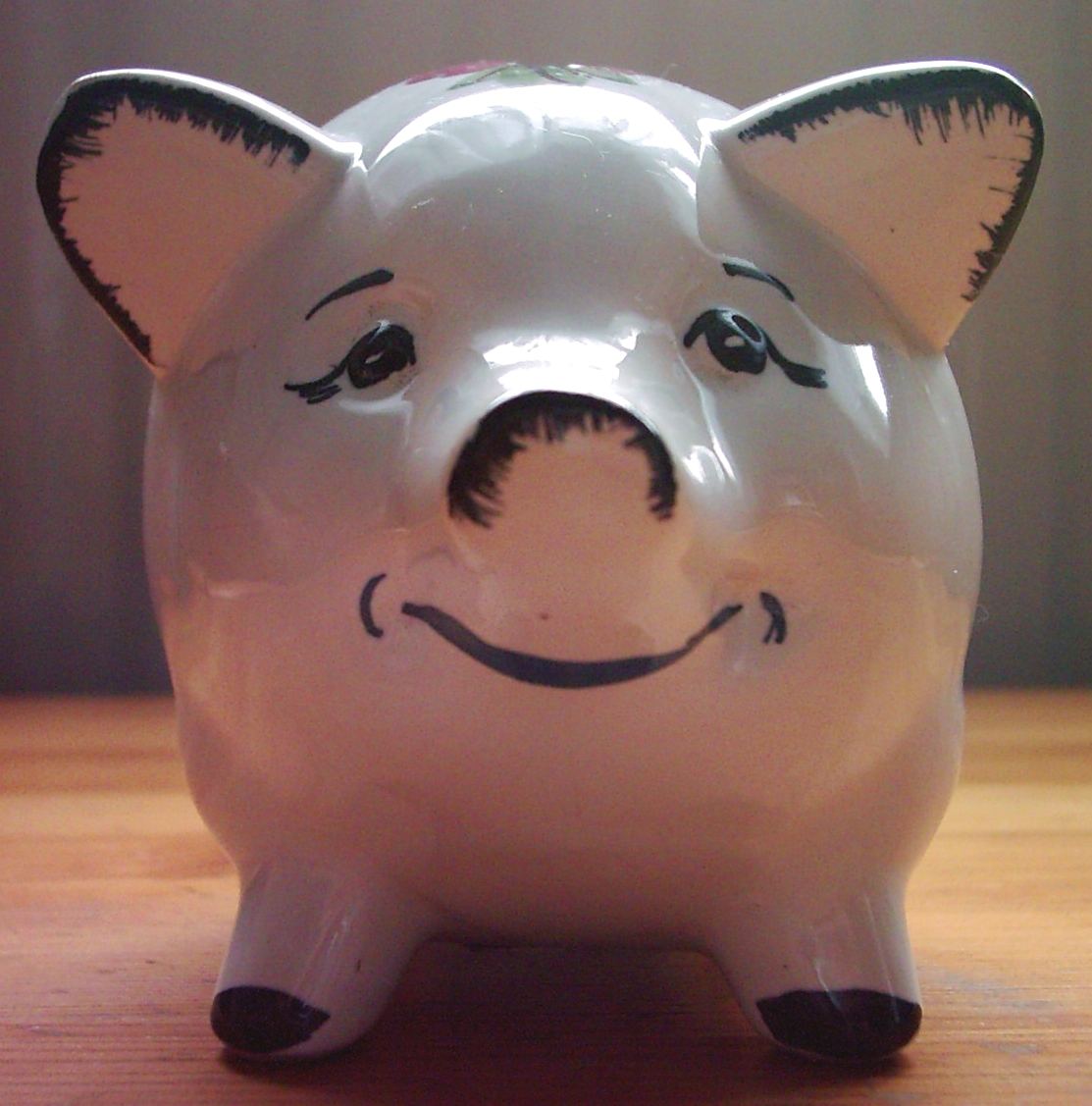 White piggy bank with a smiling face on a wooden table