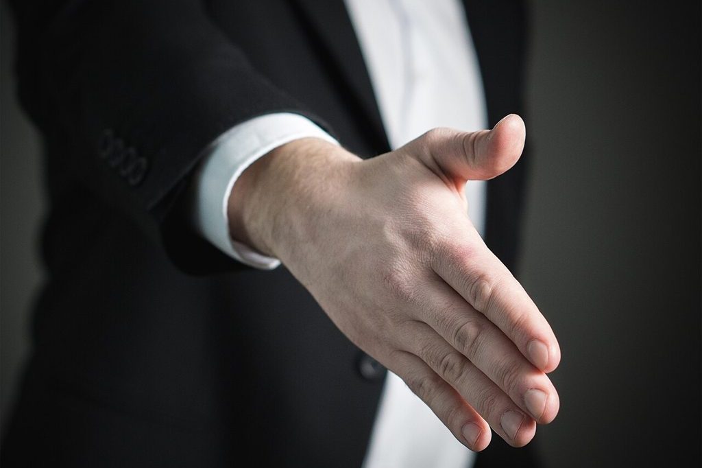 Outstretched hand in a suit, invitation to a handshake, symbolising the first client contract