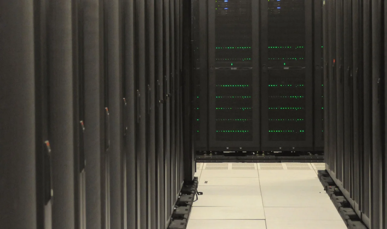 Blick in einen Rechenzentrums Gang zwischen Serverschränken mit grünen Statusleuchten