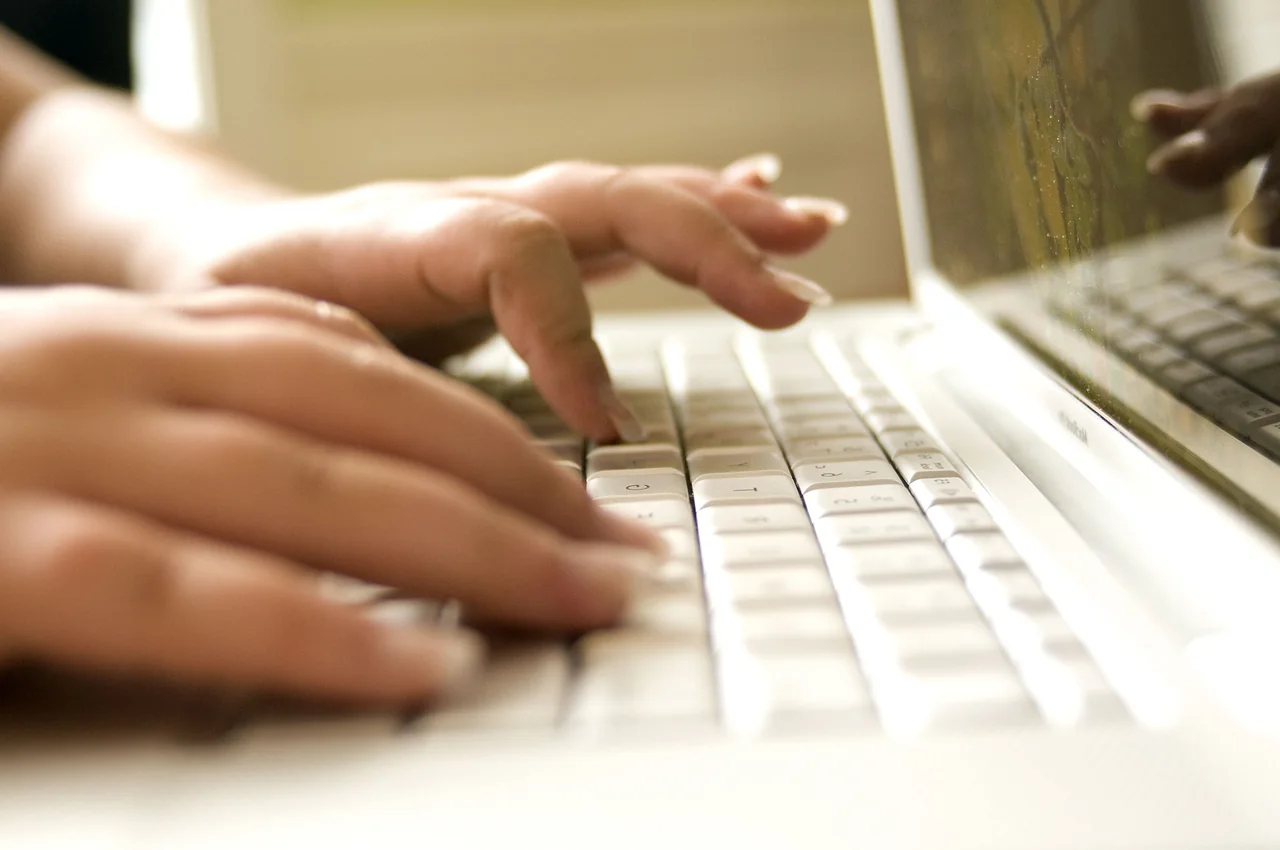 Hände tippen am Laptop: Symbolbild für die Arbeit an der eigenen Website, der Bildschirminhalt ist nicht erkennbar